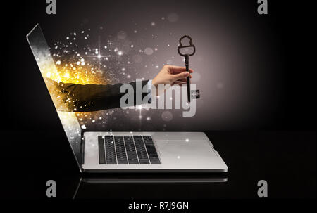 Hand with huge vintage key coming out of a laptop with sparkling effects  Stock Photo