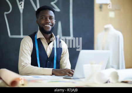 Happy male clothing designer using laptop in studio Stock Photo