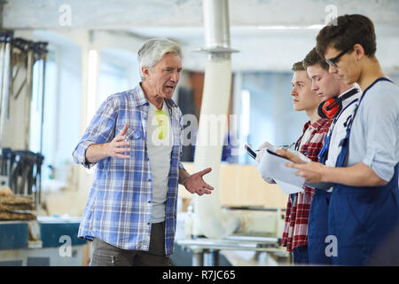 Annoyed carpenter dressing down young workers Stock Photo