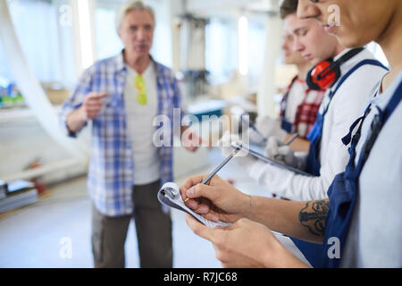 Young interns making notes while listening to carpenter Stock Photo