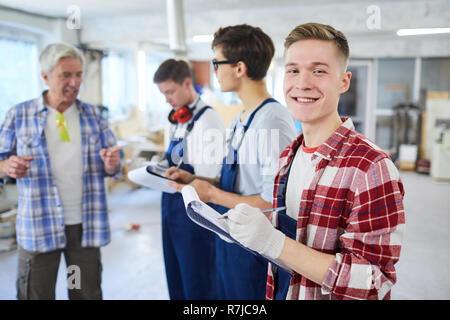 Content young carpentry worker making notes in clipboard Stock Photo