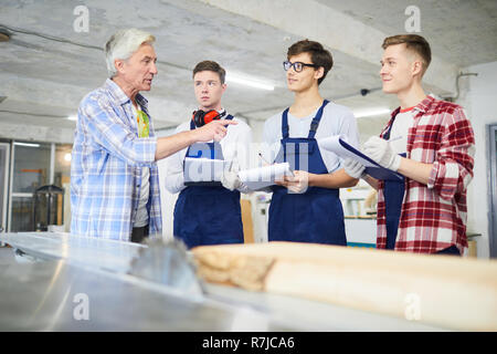 Carpenter answering questions of young employees Stock Photo