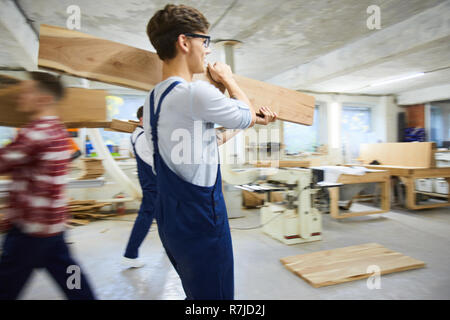 Cheerful movers carrying wooden planks Stock Photo