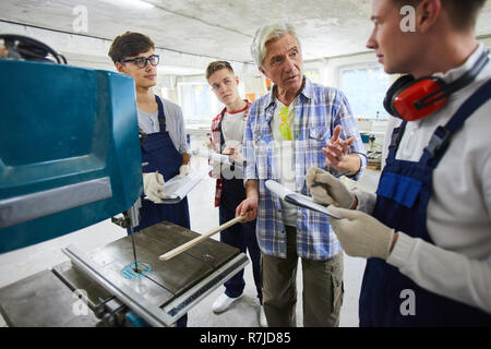 Carpenter explaining how to works with drilling machine Stock Photo