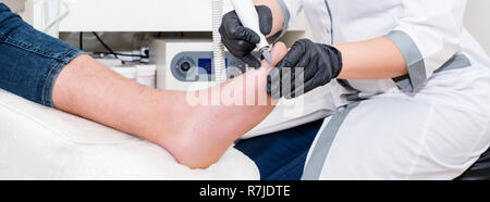Podology treatment. Podiatrist treats foot. Podiatry doctor or dermatologist treats the patient in modern clinic Stock Photo