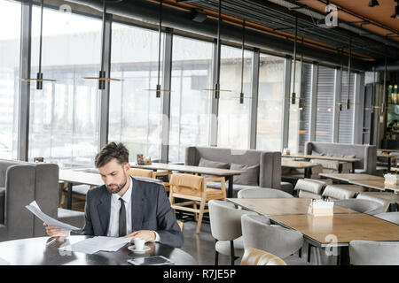 Businessperson on business lunch at restaurant sitting drinking espresso looking at documents Stock Photo
