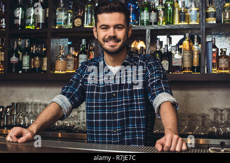 Young bartender standing at bar counter smiling confident Stock Photo