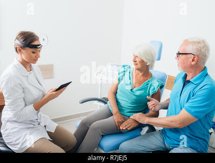 ENT Doctor talking with senior patients in doctors office Stock Photo