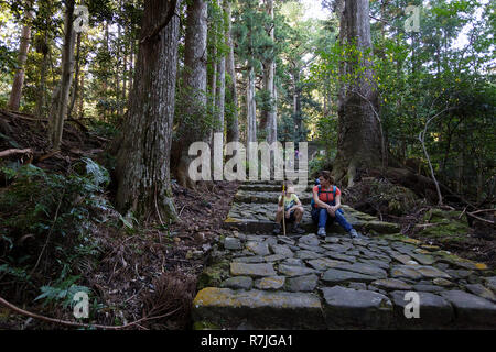 Mother and son sitting on steps in Kumano Kodo at Daimon-zaka, a sacred trail designated as a UNESCO World Heritage site in Nachi, Wakayama, Japan. Stock Photo