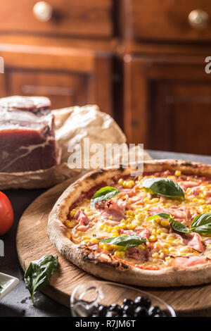 Italian pizza cardinale with ham prosciutto tomatoes corn and basil. Stock Photo