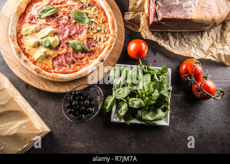 Pizza Quatro Stagioni four seasons traditional italian meal from artichokes mushrooms tomatoes ham prosciutto parmesan cheese and basil -  Top of view Stock Photo