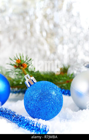 New Year background with blue and silver Christmas balls in snow, spruce green branches on light background. Xmas decoration. Merry christmas. Stock Photo