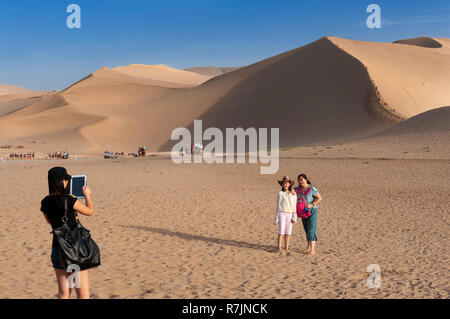 Dunhuang, China - August 8, 2012: Chinese tourists at the Crescent Moon Lake near the city of Dunhuang, in the Gansu Province, China. Stock Photo