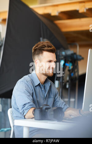 Side view portrait of handsome male photographer working in studio using computer against lighting equipment Stock Photo