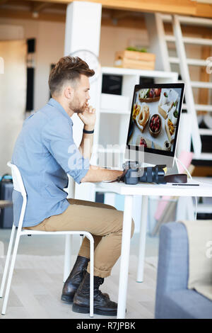 Full length side view portrait of male photographer editing photos using computer in studio Stock Photo