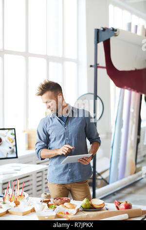 Portrait of handsome photographer using digital tablet while preparing set in studio Stock Photo