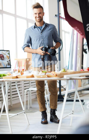 Full length portrait of smiling photographer looking at camera while working in photo studio Stock Photo