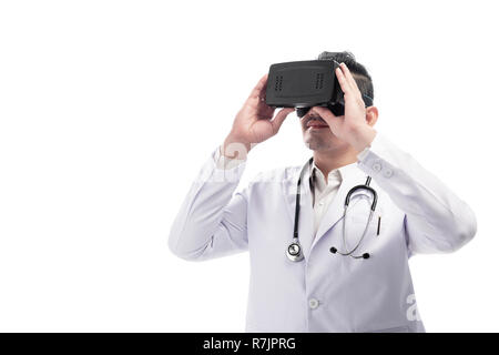 Young asian doctor man with white lab coat and stethoscope using virtual reality standing isolated over white background Stock Photo