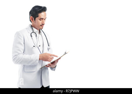 Handsome asian doctor man wearing lab coat reading notes on the clipboard standing isolated over white background Stock Photo