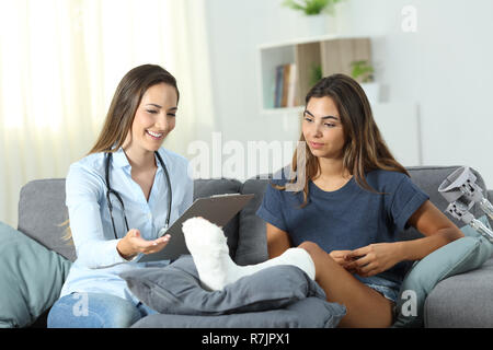 Happy doctor and patient talking sitting on a couch in the living room at home Stock Photo