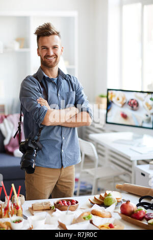 Portrait of handsome professional photographer posing in photo studio and smiling at camera Stock Photo
