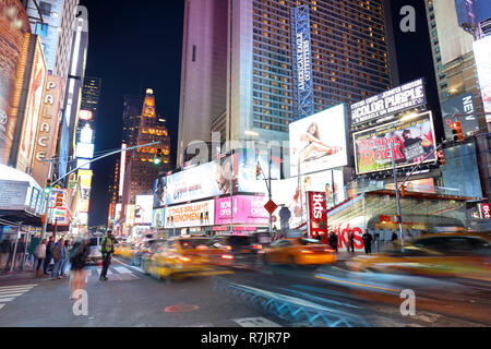 NEW YORK, USA - APRIL 12: The architecture of the famous Times Square in New York city, USA with its neon lights and panels at night and a lot of tour Stock Photo