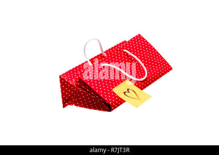 Gift bag with heart shape message, written by hand. Red polka dot paper bag isolated on white background. Stock Photo