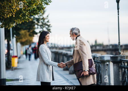 Man and woman business partners standing outdoors in city of Prague, shaking hands. Stock Photo