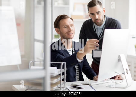 Portrait of two professionals looking at computer screen while working in modern office, copy space Stock Photo