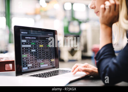 An industrial woman engineer in a factory using laptop. Stock Photo