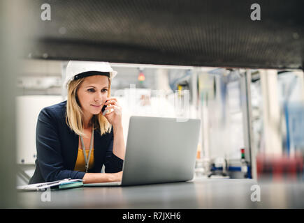 Industrial woman engineer in a factory using laptop and smartphone. Stock Photo