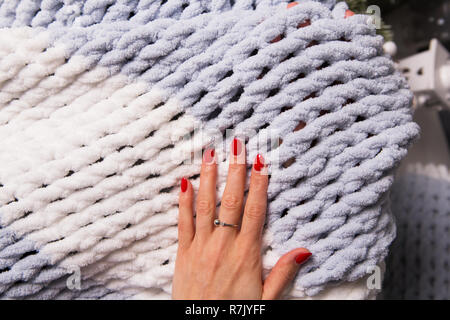The girl is holding a knitted soft blanket in her hands, close up. Stock Photo