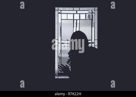 A girl's silhouette looking out a window Stock Photo