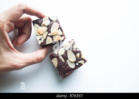 Woman's hands picks chocolate brownie isolated on white background Stock Photo