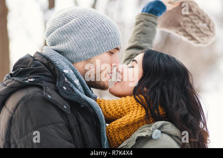 Happy woman and man, kissing, and huging, spending time together enjowing eachother, snow, life, winter. Portrait wonderful young couple wearing styli Stock Photo