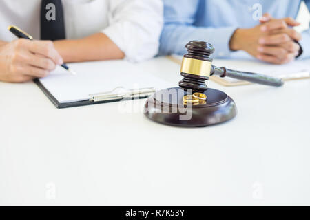 Angry couple arguing telling their problems to Judge gavel deciding on marriage to conclude an agreement on the divorce. They quarrel and argue with e Stock Photo