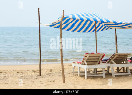 Two chaise lounges under a canopy on the beach near the ocean Stock Photo
