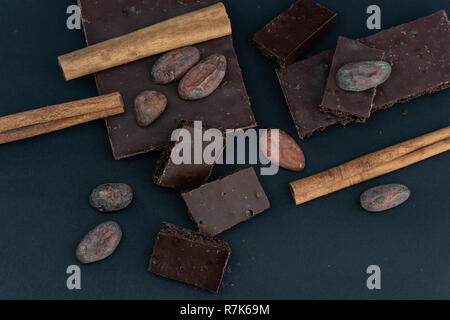 Still life of chocolate, cinnamon and cocoa beans on a dark background. Stock Photo