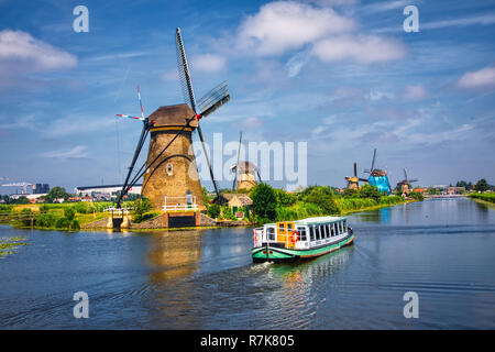 Kinderdijk, Netherlands - June 27, 2018: Netherlands rural lanscape with tourist boat and windmills at famous tourist site Kinderdijk in Holland. This Stock Photo