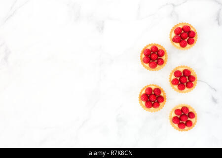 Raspberry mini tarts, tartlets, with lemon cream on white marble with copy space. Top view. Stock Photo