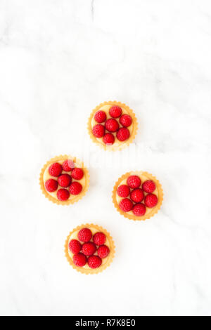 Raspberry mini tarts, tartlets, with lemon cream on white marble background with copy space. Top view. Stock Photo