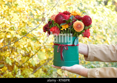 Beautiful man in a suit holding hands festive green box with delicate flowers.Gift to Women's Day. Close up side view.Concept for wedding, birthday, e Stock Photo