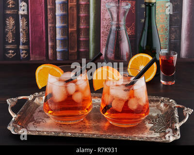 Two glasses of Aperol Spritz, an aperitif cocktail consisting of prosecco, Aperol and soda water, with ice cubes and orange slices. Stock Photo