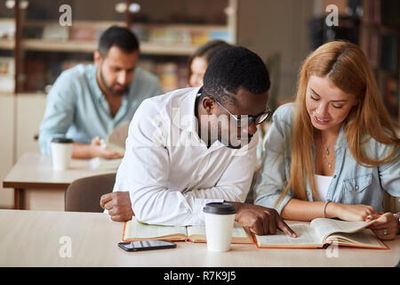 group of happy students reading books and preparing to exam in library Stock Photo