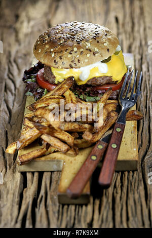 homemade cheeseburger and French fries on rustic wooden background Stock Photo