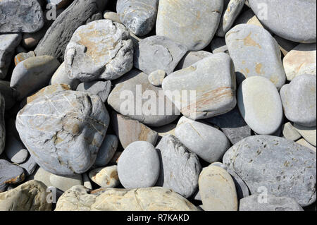 Grey stones or rocks on a beach in wales near Tenby, rounded and eroded by the action of the sea and weather. Stock Photo