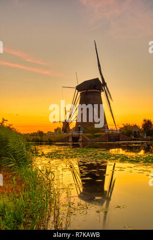 view of traditional windmills at sunset in Kinderdijk, The Netherlands. This system of 19 windmills was built around 1740 and is a UNESCO heritage sit Stock Photo