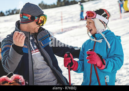 Beautiful young father and daughter enjoying in ski vacations. They are posing on sunny winter day and looking each other with smile. Stock Photo