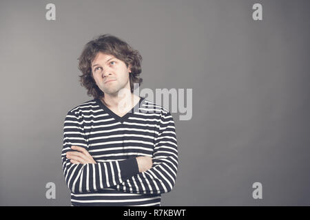 Portrait of caucasian man with bored fed up expression, looks displeased up, being tired to explain his wife where he was at night. Shaggy guy in stri Stock Photo