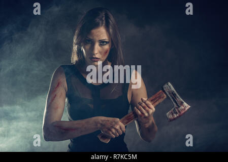 Beautiful dangerous girl with rusty axe. Looking at camera. Stock Photo